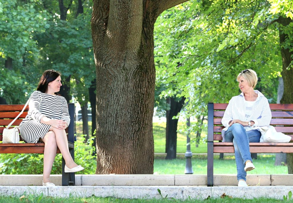 Two women on park benches talking to each other